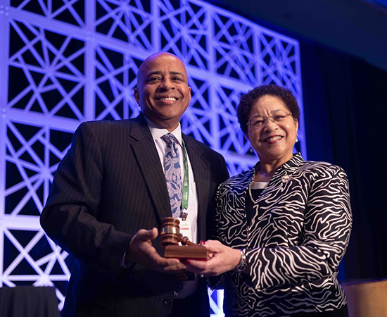 Outgoing board chair President Anderson passes the gavel to President Rochon. Photo by Rhonda Nunn.